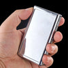 A hand holds a silver metal cigarette holder with a rectangular design against a black background.