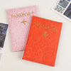 Two pink and orange leopard print PU leather passport holders with gold foil text and airplane emblems.