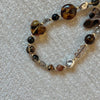 A beaded phone lanyard featuring various shades of amber, brown, and clear glass beads.