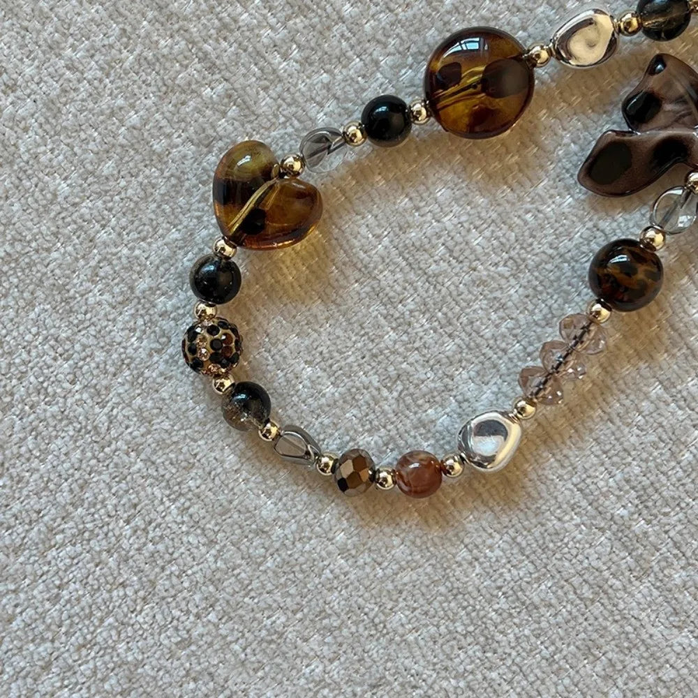 A beaded phone lanyard featuring various shades of amber, brown, and clear glass beads.