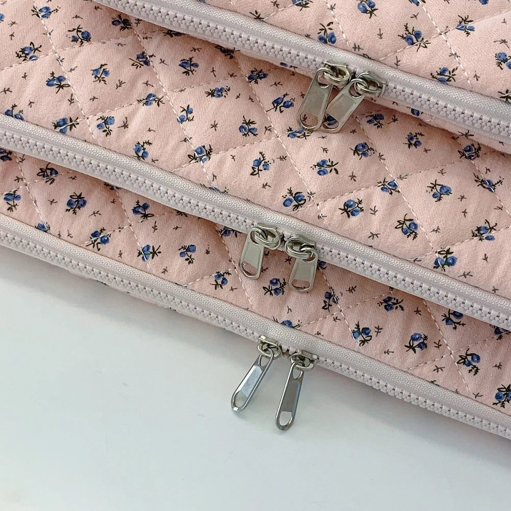 Funda acolchada para laptop floral rosa con tiradores de cremallera plateados.