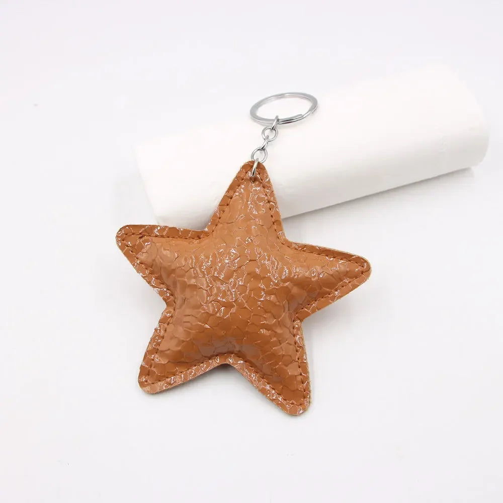 A brown leather star shaped key chain pendant with a silver keyring, displayed on a white background.