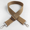 A tan woven leather handbag strap with an arrow jacquard pattern, shown crossed.