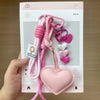 Pink handmade PU leather heart keychain with braided rope and charm.