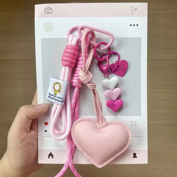 Pink handmade PU leather heart keychain with braided rope and charm.