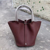 Tiefburgunder roter Leder-Bucketbag mit hellem grauem Stoffgriff auf Beton