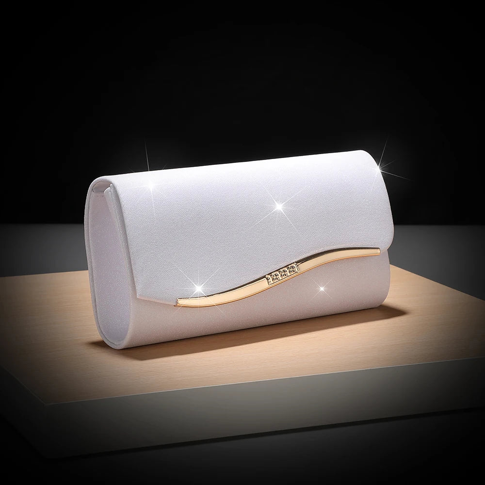 A white envelope clutch with a gold chain detail resting on a wooden surface.