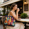 Una mujer sostiene un bolso de tela acolchada vintage mientras está sentada en una mesa de café al aire libre.