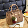 A tan vintage PU leather tassel handbag resting on a wooden surface with a quilted dark leather background.