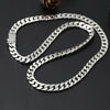 A silver punk charm bracelet with a padlock clasp is laid out on a dark surface.