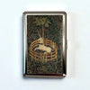 A vintage metal card holder with an engraved design of a silhouette of a deer within a circular wooden frame on a dark backgr