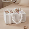 A white flannel diaper caddy organizer filled with various baby items, shown on a beige surface.