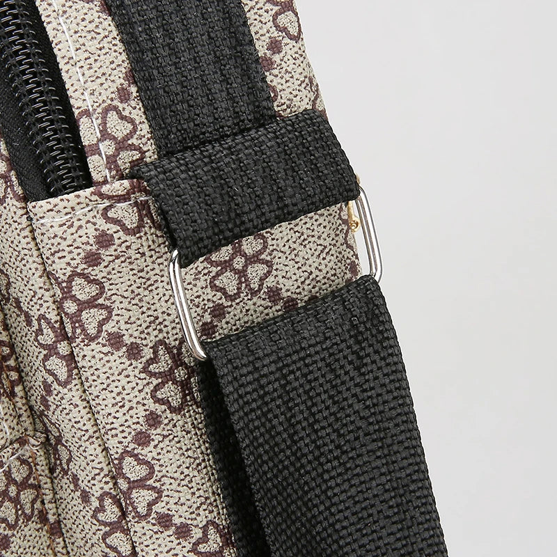 Close-up of a beige and brown patterned fabric strap with black webbing and silver hardware for a men's crossbody sling bag
