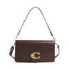 A brown leather shoulder bag with a gold initial detail and a long strap.