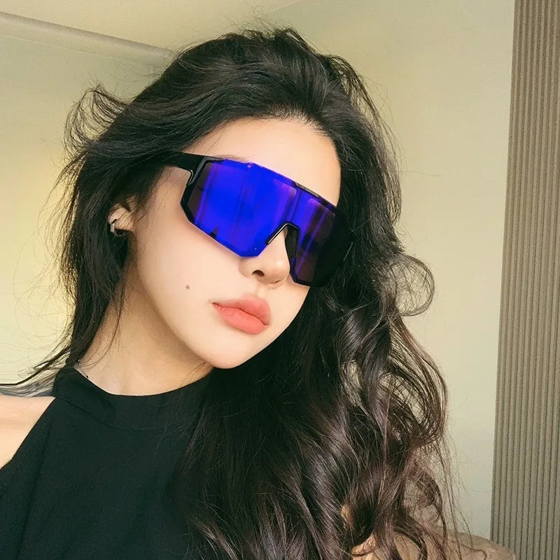 Una mujer con cabello largo y oscuro vistiendo gafas de ciclismo azules UV400 contra un fondo claro.