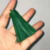 A hand holds a vibrant green leather tassel fringe craft supplies set.