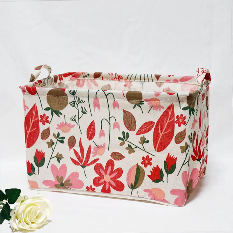 A fabric storage basket with handles featuring a floral pattern in shades of red, pink, and green.