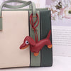 A light beige and olive green leather bag featuring a dachshund charm.