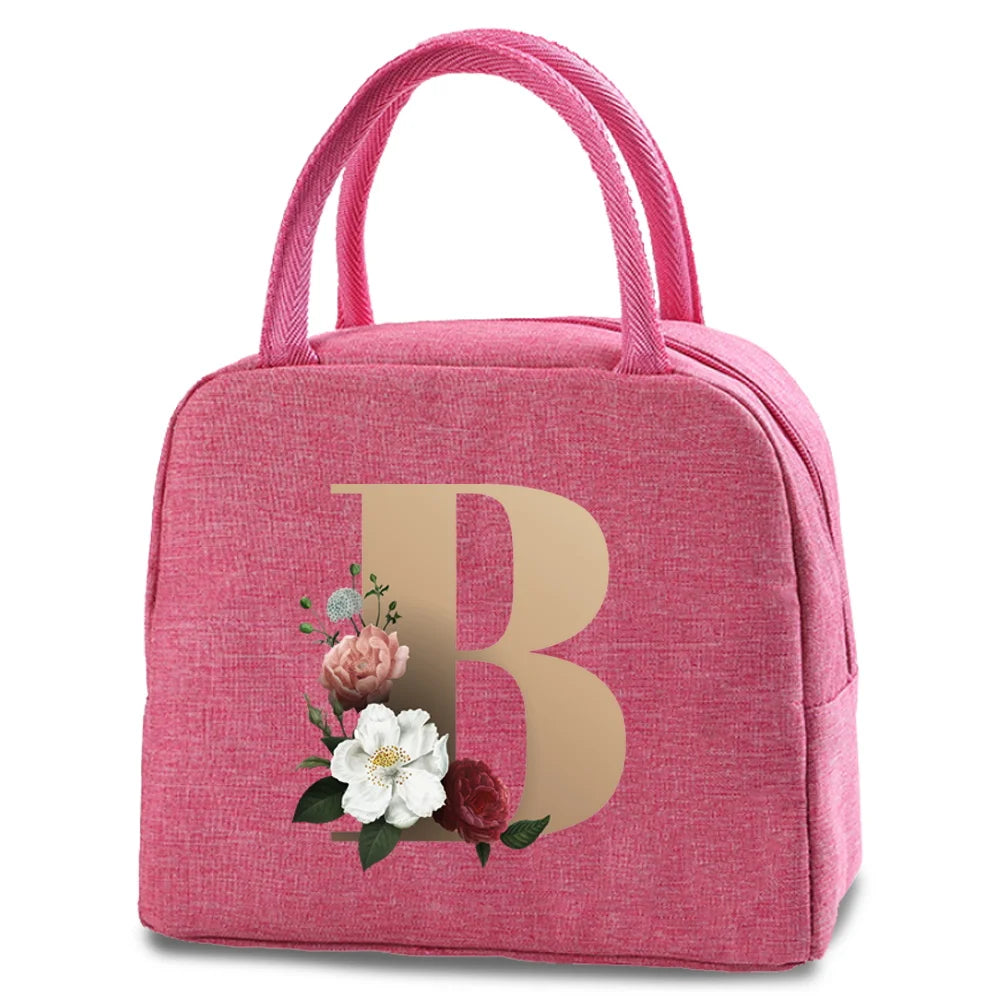 A pink insulated canvas lunch bag with a gold letter B print and pink fabric handles.
