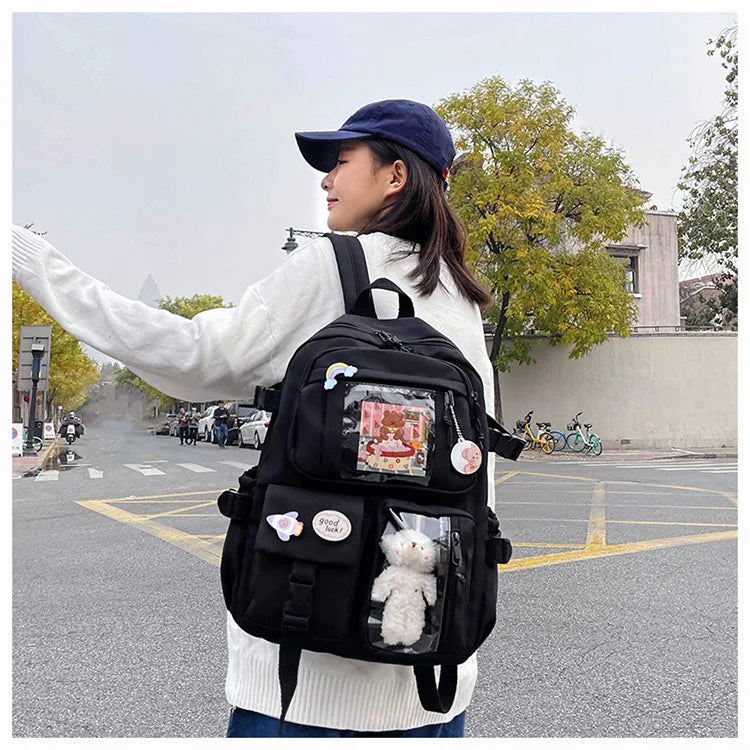A woman wearing a white sweater and blue hat carries a large black backpack outdoors.