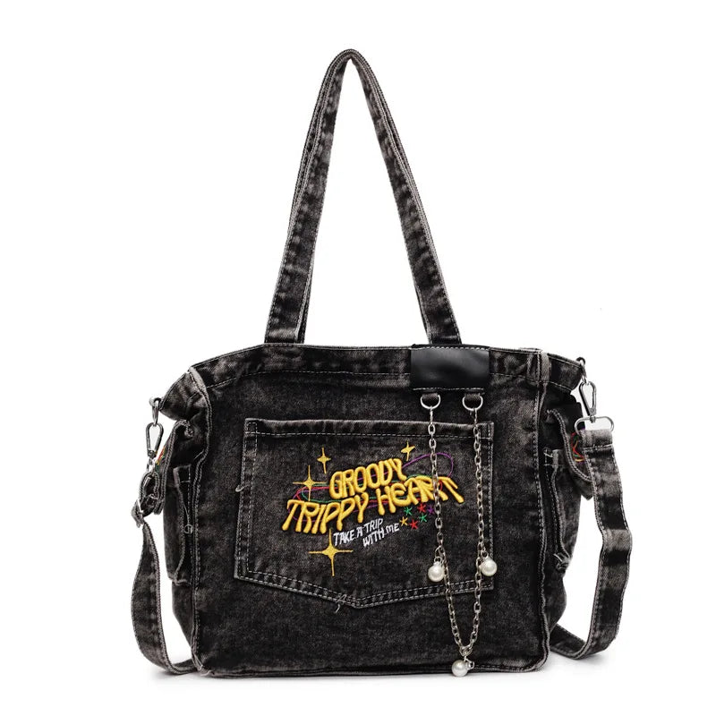 A black denim crossbody bag featuring embroidered text on the front pocket.