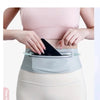 A woman is wearing a gray waist pack designed to fit 7.5-inch phones, shown against her torso.