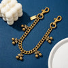 Colgante de bolso de cadena de cereza vintage dorada sobre una superficie azul oscuro junto a cuentas blancas.