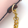 A close-up of a thick gold metal chain replacement strap attached to the corner of a pink leather purse.
