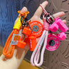 A hand holds a colorful fitness keychain featuring an orange dumbbell and pink kettlebell charms on a lanyard.