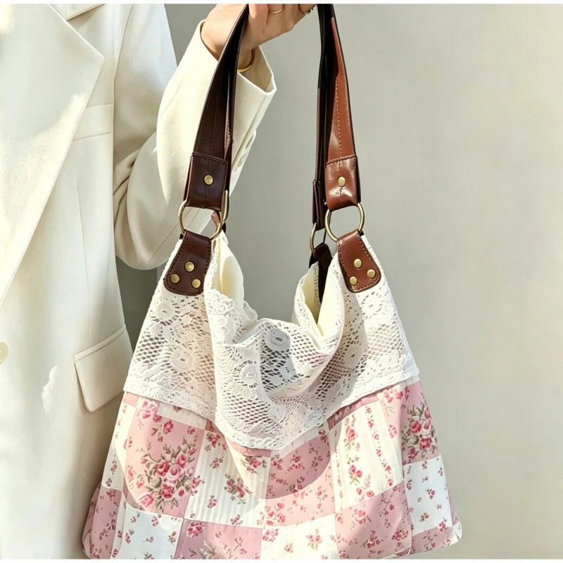 A close-up of a bohemian floral patchwork shoulder bag with white lace fabric and brown leather straps.