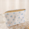 White corduroy cosmetic bag with a light blue starfish pattern lying on lace fabric.