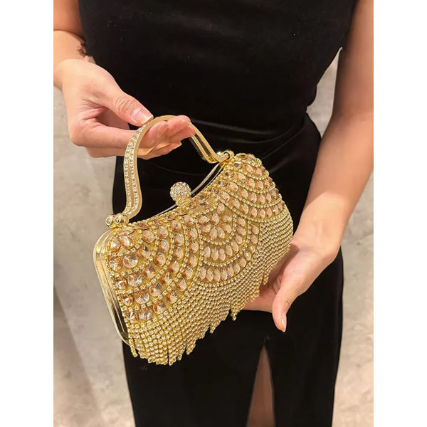 A hand holds an elegant gold diamond rhinestone evening clutch bag with a golden tassel.
