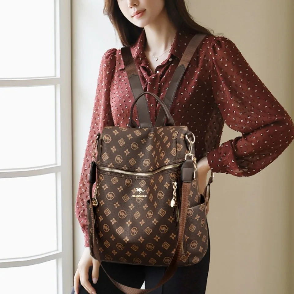 A woman wearing a brown patterned shirt and a genuine leather backpack with gold hardware.