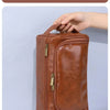 A brown leather wash bag with a handle is shown being held, demonstrating its convenient design.
