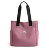 A pink nylon shoulder tote bag with black straps.