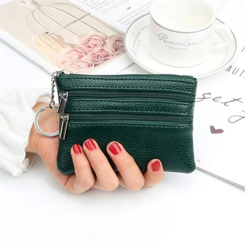 A dark green PU leather clutch wallet is held by a hand next to a white cup and some papers.