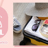 A clear makeup bag with a straw handle and a chenille letter design is shown inside an open suitcase.