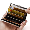 A hand holds a slim card holder wallet displaying various credit cards including Visa and Mastercard.