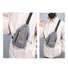 A light gray lightweight oxford cloth crossbody bag worn by a person in a beige jacket.