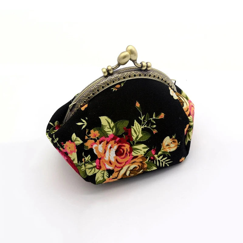 A vintage rose print canvas coin purse in black fabric with floral embroidery and a gold-toned clasp.