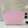A pink corduroy makeup organizer bag with an octagonal design is shown on a white surface.
