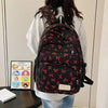 A black nylon travel backpack with a red bow print is worn by a person.