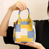 A hand holds a yellow and blue geometric colorblock knitted bucket bag.