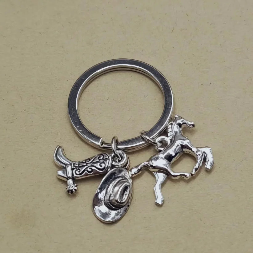 Silver keychain set featuring a western cowboy boot, hat, and horseshoe charms.