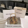 A gold chain crystal-embellished evening clutch displayed in a white box with the Mack Jenkins brand visible.