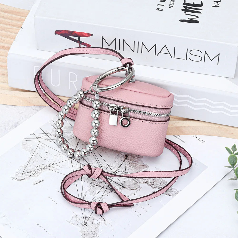 A pink leather coin purse with a silver chain and lanyard is displayed on a map background.