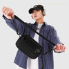A person holds up a black PU leather crossbody bag with an adjustable strap against a light background.