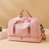A pink quilted nylon travel duffle bag with pink straps resting on a light beige surface.