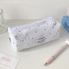 Weiches Polka-Dot-Etui mit Reißverschluss und kleines Etikett auf heller Oberfläche.