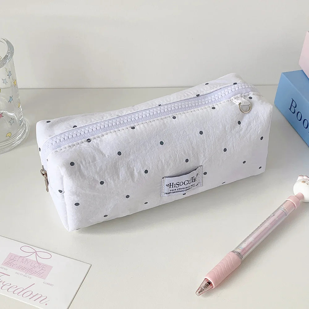 Weiches Polka-Dot-Etui mit Reißverschluss und kleines Etikett auf heller Oberfläche.